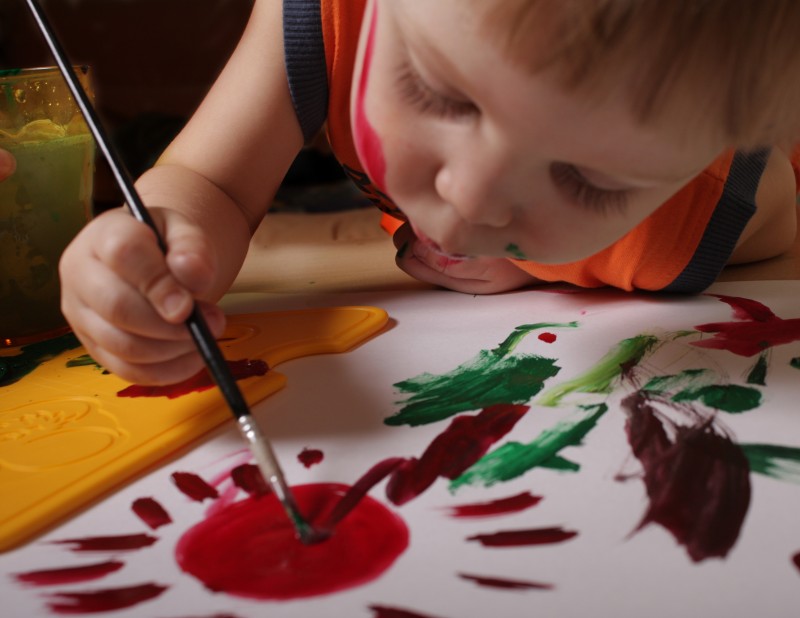 Niño o niña pintando con un pincel sobre papel.